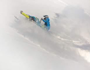 Pro snowmobiler makes a turn and lets a flurry of snow spray from under the caterpillar. sports snowmobile in the mountains. radial turn of the snowmobile on a steep slope. Winter fun moto extreme