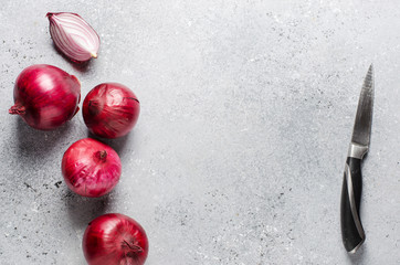 Lots of red onions on a gray concrete background. Flat top view