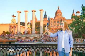 Obraz premium Young Woman Taking selfie against The Catalania National Museum. Young woman with digital gadget in the old historical streets of Barcelona.