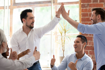 Diverse business partners giving high five celebrating successful work
