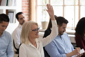 Middle aged woman raising hand to ask question at seminar