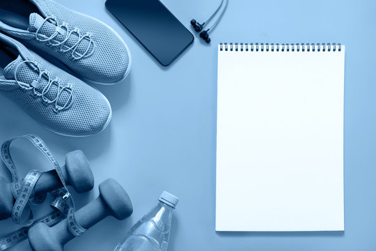 Sport And Fitness Equipment With Sneakers And Headphones On Blue. Blank With Space For Text. View From Above. Trendy Color Classic Clue Of The 2020 Year.