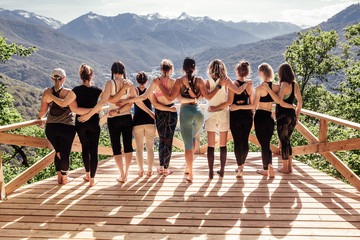 Rear view of a group of slim body-positive sportive active friendly women doing fitness and yoga together among mountain ecologically clean nature. Ecological Sports Tourism Concept - Powered by Adobe