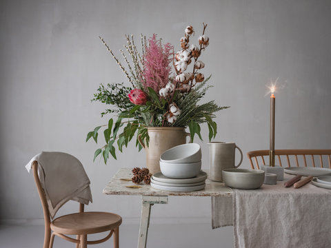 Tisch wird festlich gedeckt zur Weihnachts- und Winterzeit mit großer Blumendekoration