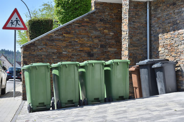 Green trash cans are standing against the wall. Garbage containers for sorting garbage in a European city