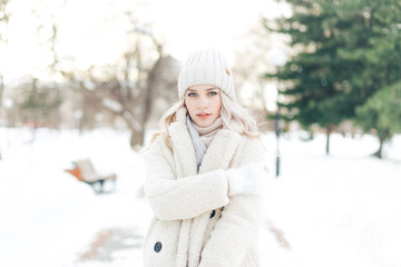 Blonde girl in warm clothes in the winter in the park
