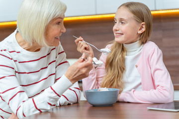 Obraz na płótnie Canvas Granddaughter and her grandmother eating dessert together