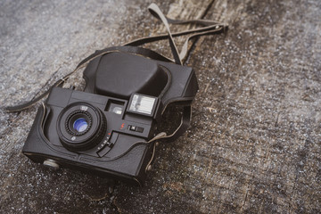 Retro black camera lying on the wooden background