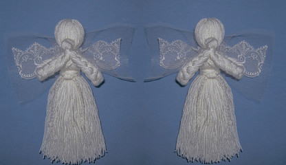 Two white angels with wings on blue background. Prayed thread dolls as a symbol of love, charity and faith. Christmas and New Year decoration design