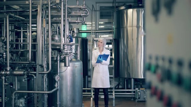 Quality control of production line at a factory. A person checks metal tanks at a dairy factory.
