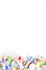 Sweet Easter baking cooking background with traditional Easter bunny and egg cookies, sugar sprinkles, ingredients, utensils. White table background copy space layout