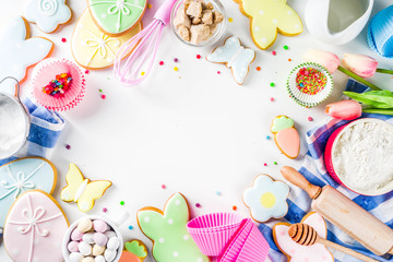 Sweet Easter baking cooking background with traditional Easter bunny and egg cookies, sugar sprinkles, ingredients, utensils. White table background copy space layout