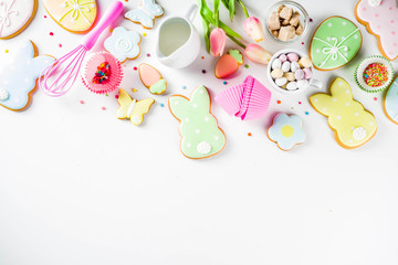 Fototapeta na wymiar Sweet Easter baking cooking background with traditional Easter bunny and egg cookies, sugar sprinkles, ingredients, utensils. White table background copy space layout