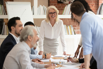 Positive aged businesswoman and diverse colleagues at office meeting