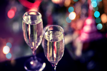 Two glasses of champagne nearby Christmas tree with bokeh