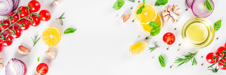 Cooking background with spices, vegetables and herbs fresh basil, rosemary, tomato, garlic, onions, lemon on a white kitchen table. Layout top view copy space. Healthy ingredients for cooking