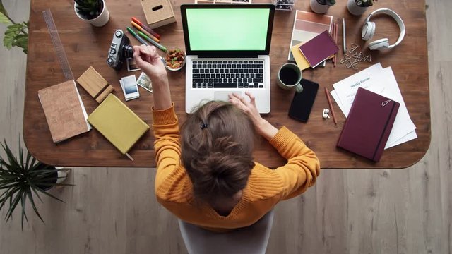 Flat lay of female student sitting at desk at computer screen and working