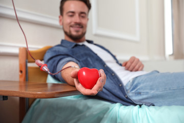 Young man making blood donation in hospital, focus on hand