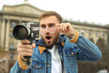 Young man with vintage video camera on city street