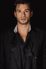 handsome man in suit looking at camera isolated on black