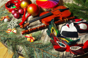 Carnival still life. Carnival masks, violin, flute, maracas, tambourine on a decorated table.