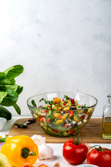 Bowl full of salad from different eco vegetables with ingredients and spices on the table. Healthy diet food concept.