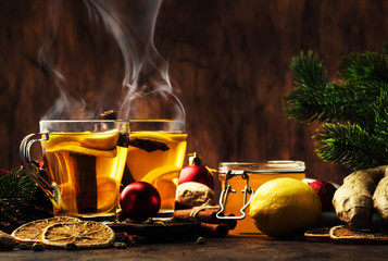 Winter hot tea with fruit, lemon and spices in glass cup with steam in Christmas or New Year's...