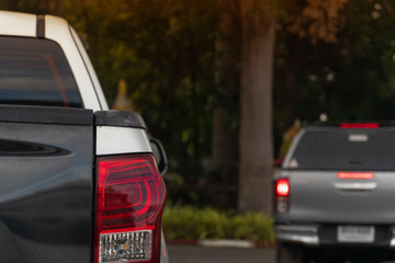 The back of the pickup truck that sees the taillight And with a blurry background image of a car parked in the evening garden.