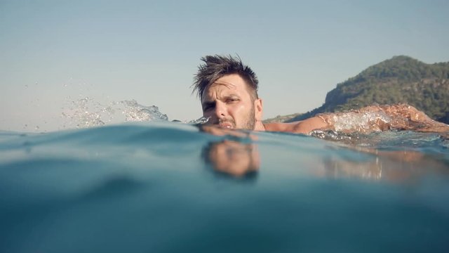 Swimming Man On Blue Sea Underwater.Underwater Man Swimming In Slow Motion With Air Bubbles.Air Bubbles In Water.Water Drops Falling And Splashing On Glassy Water Surface Blue Ocean