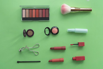 A collection of make up and cosmetic products arranged on a pastel green background.beauty concept.