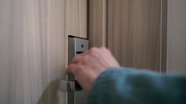The girl inserts a key card into the door of the hotel room and goes inside