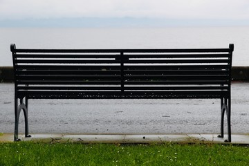 bench on grass facing the sea
