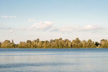 Beautiful summer landscape. A river and trees on the opposite bank. Rest by the river.
