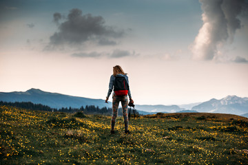 Young hiker, backpaker girl with camera in hands standing on the top of the mountains.summer season.