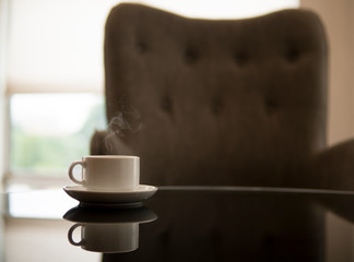 Hot white cup with grey chair on background. Tea or coffee break concept.