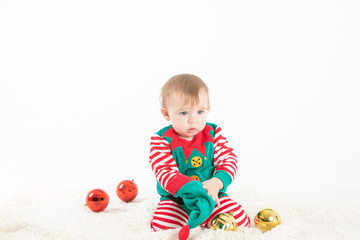 Fototapeta na wymiar Baby disguised elf with hat removed from head rolled from Christmas balls