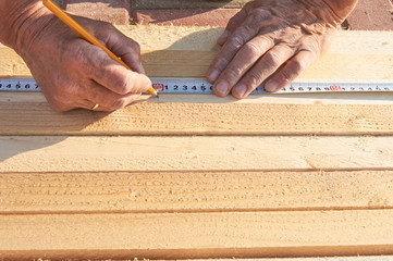 Worker measures wooden beams on the tile floor Construction works