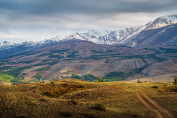 Dawn in the Chuy valley, a tourist minibus on a field road on a hillside. Russia, mountain Altai