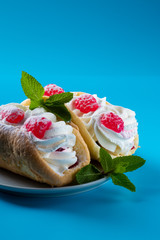 Air cake with raspberries in a plate on a blue background