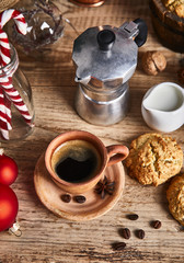 Hot coffee in clay cup with star anise on old wooden board with homemade cookies. Christmas composition with festive decor.