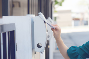 Woman hand pull the mail / peper / advertisment from the mailbox that hange on pillar of her house