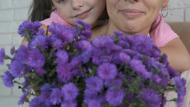 A blue bouquet for mother. Portrait of a happy little girl with mom and flowers.