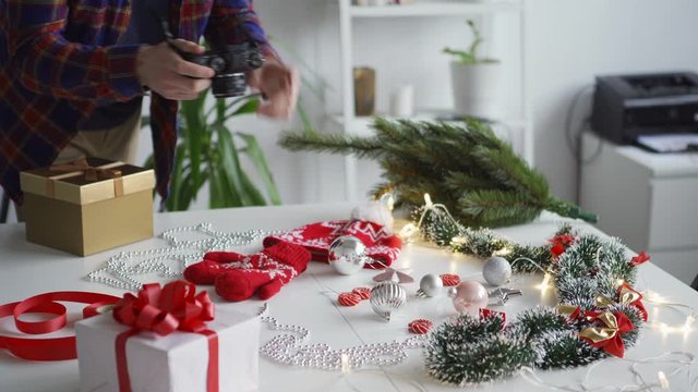 Closeup hands of unrecognizable male photographer arranging objects on table and taking photos of Christmas flatlay with camera