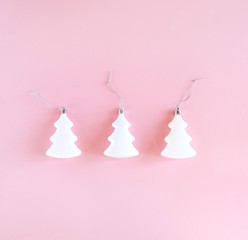 Three white christmas and new year trees on pastel pink background. Minimalistic holiday concept. Square, top view, flat lay.