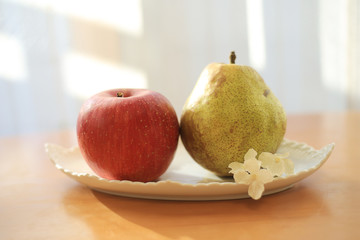 机の上のお皿に乗った林檎と洋梨