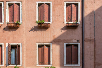 Fototapeta na wymiar The walls and windows of the ancient colorful houses in Venice, Italy