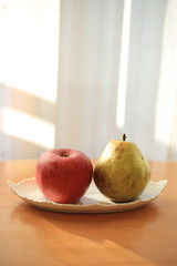 机の上のお皿に乗った林檎と洋梨