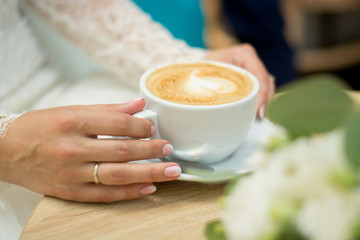 The hands of the bride and groom.  Cup of coffee in hands.Wedding.