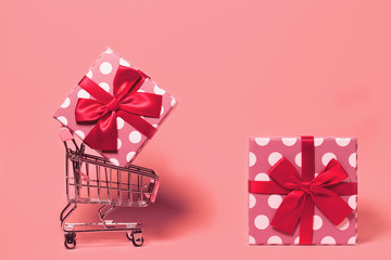 Small decorative trolley with present box on bright colorful background. Christmas or birthday gift. Sales and shopping concept.