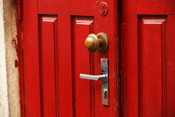 Red wooden door with round ornate handle and traditional handle
